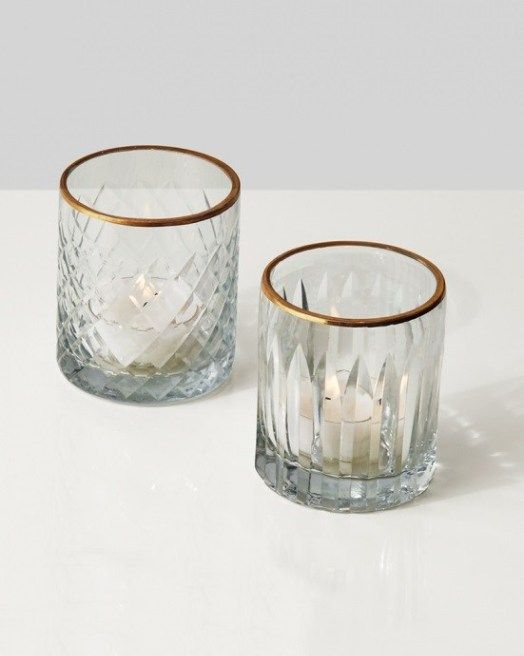 two clear glass tumblers with gold rims on a white table top next to each other