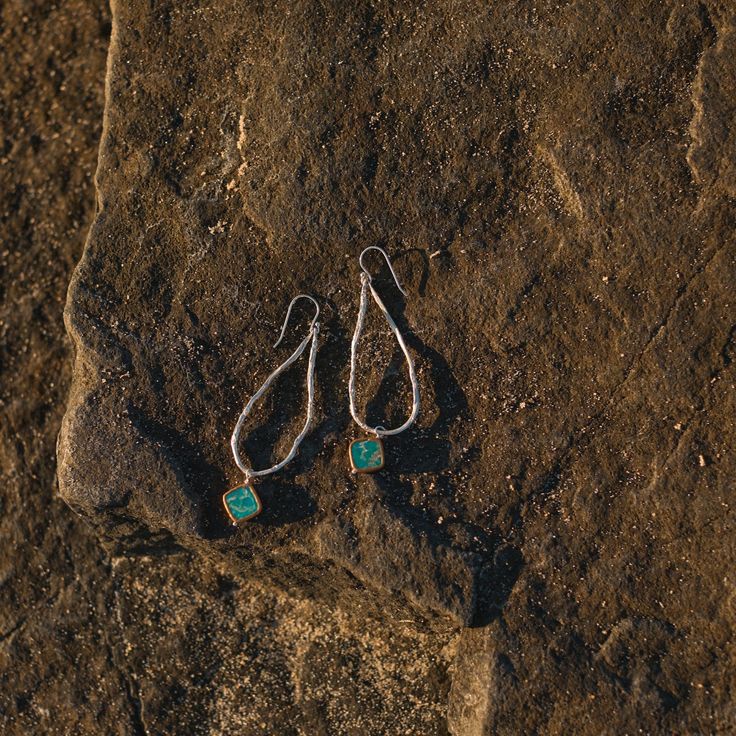 A turquoise pendant dangles from a textured silver-casted vine. 2.5" long. Turquoise Hand Forged Drop Earrings, Hand Forged Turquoise Sterling Silver Earrings, Turquoise Sterling Silver Long Drop Earrings, Turquoise Long Drop Sterling Silver Earrings, Hammered Turquoise Sterling Silver Jewelry, Turquoise Hammered Sterling Silver Jewelry, Green Oxidized Drop Earrings, Green Sterling Silver Hammered Jewelry, Green Hammered Sterling Silver Jewelry