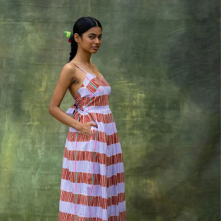 This playful striped sundress features a gathered design and a charming back bow detail, perfect for sunny days. With an inseam pocket for added convenience, it blends style and functionality seamlessly. Ideal for effortless summer outings, this dress combines a fun, flirty silhouette with practical touches. Striped Cotton Sundress For The Beach, Striped Cotton Maxi Dress For Vacation, Striped Cotton Beach Dress, Striped Tie Back Dress For The Beach, Tie Back Sundress For Picnic, Striped Summer Midi Dress For Beach, Sundress With Tie Back For Picnic, Summer Striped Midi Beach Dress, Striped Sundress For The Beach