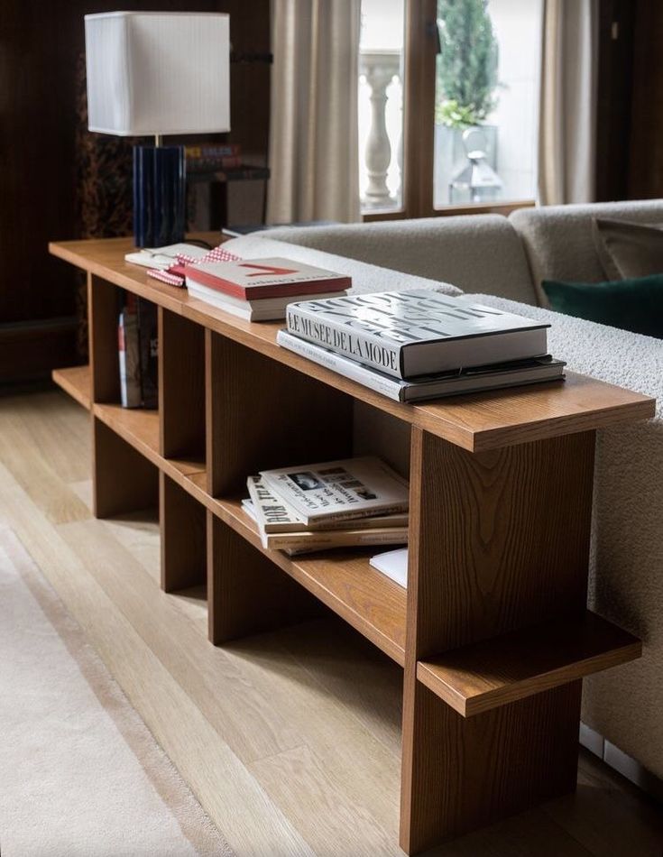 a living room with a couch, coffee table and books on top of each shelf