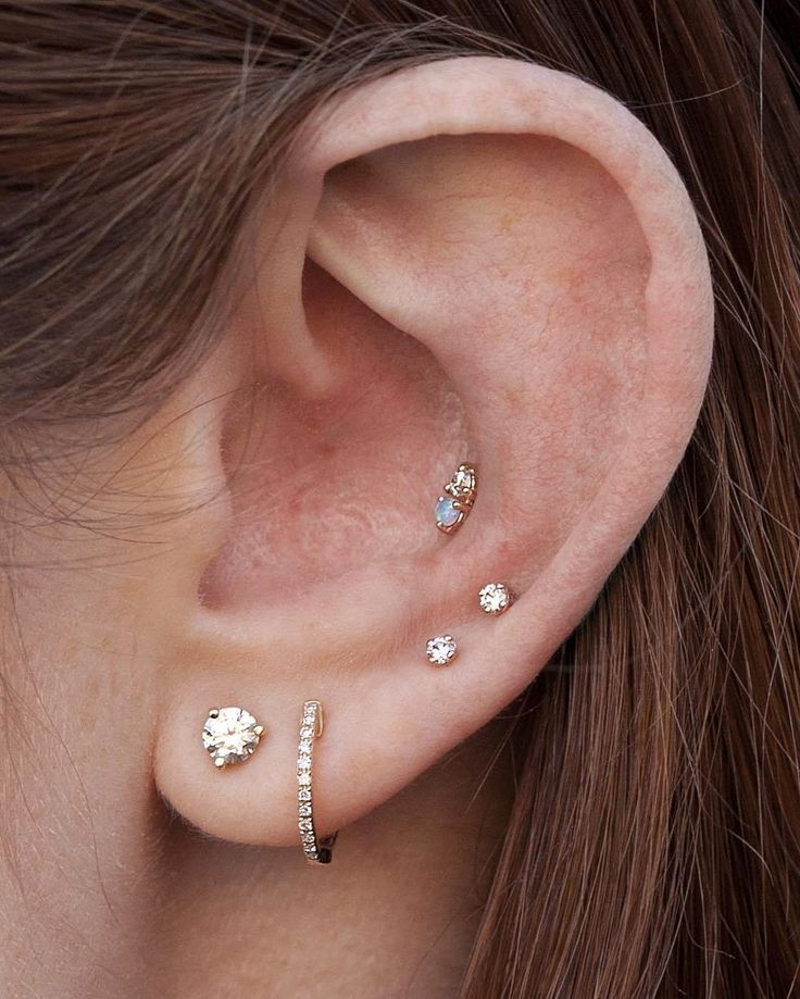 an ear with three different piercings attached to it, and the other one has a small