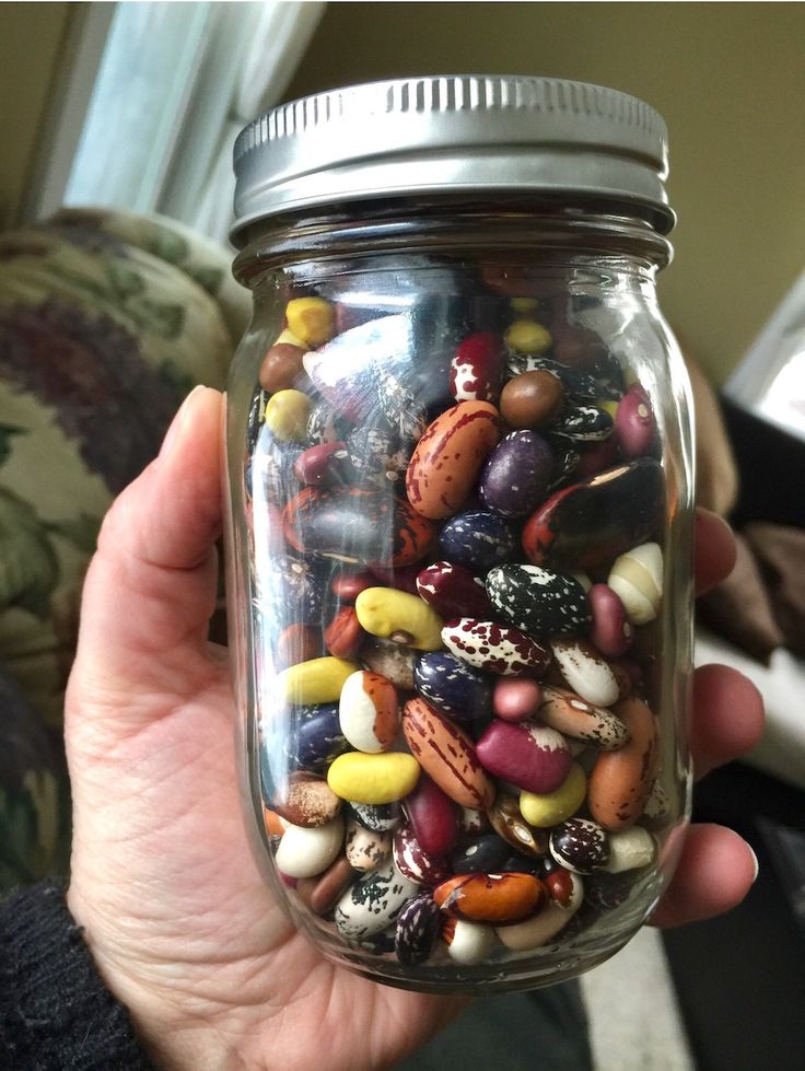 a person holding a jar filled with lots of different types of candies in it