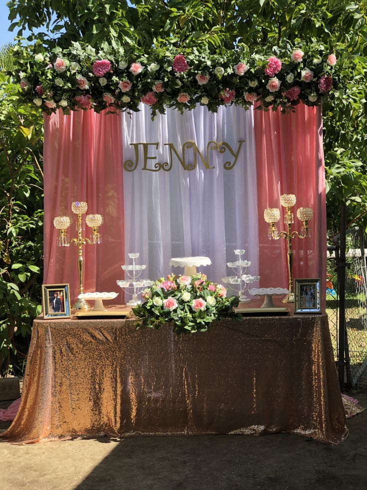 a table topped with cake and flowers under a canopy