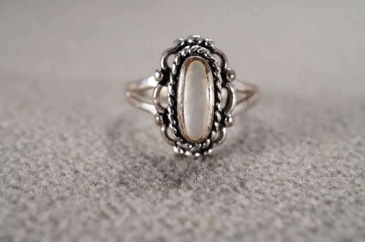 I am offering you this vintage sterling silver wedding band design ring.  This features a raised relief  single stone setting.  This has a bezel set oval shaped genuine Mother of Pearl stone set in it.  This ring is currently a size 6.5, though I am sure it could be sized up or down. Please review all of my pictures, as they are all a very important part of , my listing/descriptions. Vintage White Gold Oval Cabochon Ring, Vintage Oval Moonstone Ring Hallmarked, Oval Moonstone Ring With Bezel Setting For Wedding, Oval Moonstone Ring For Wedding With Bezel Setting, Classic Silver Oval Cabochon Ring, Antique Oval Opal Ring In Sterling Silver, Vintage Oval Hallmarked Opal Ring, Vintage Hallmarked Oval Opal Ring, Silver Ring With Bezel Setting Oval Cabochon