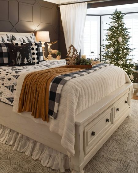 a white bed sitting in a bedroom next to a window covered in christmas tree decorations