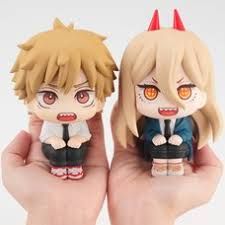 two anime figurines sitting on top of each other in their hands, one with red eyes and the other with blonde hair