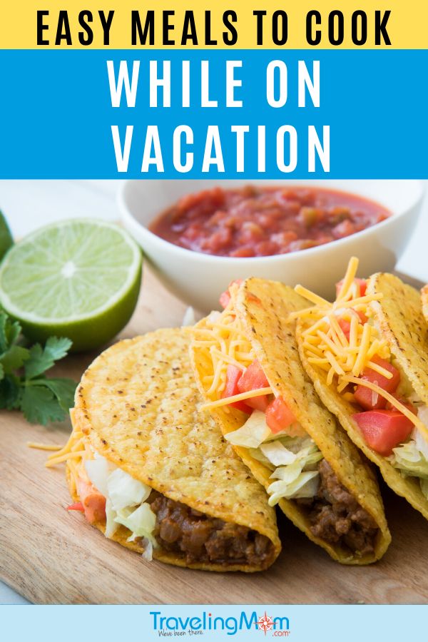 two tacos on a cutting board with salsa and guacamole in the background