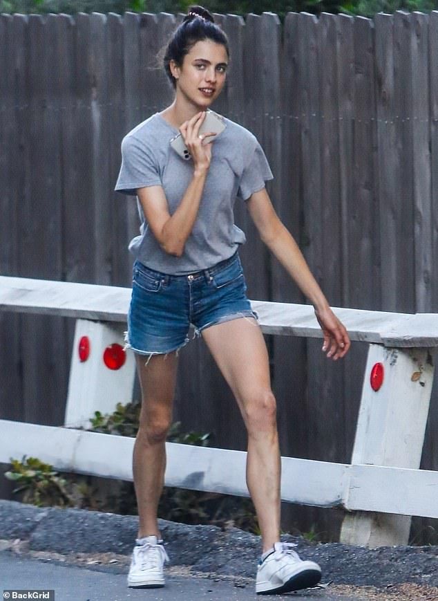 a woman walking down the street with her hand on her face