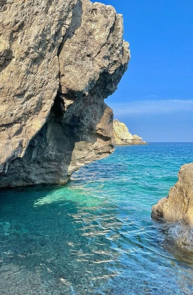 the water is crystal blue and there are large rocks sticking out of it's sides