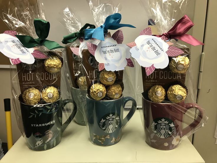 three starbucks mugs with chocolates wrapped in cellophane and bow on them