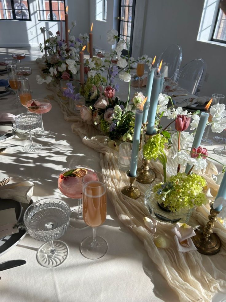 a long table is set with candles and flowers in vases, plates and glasses