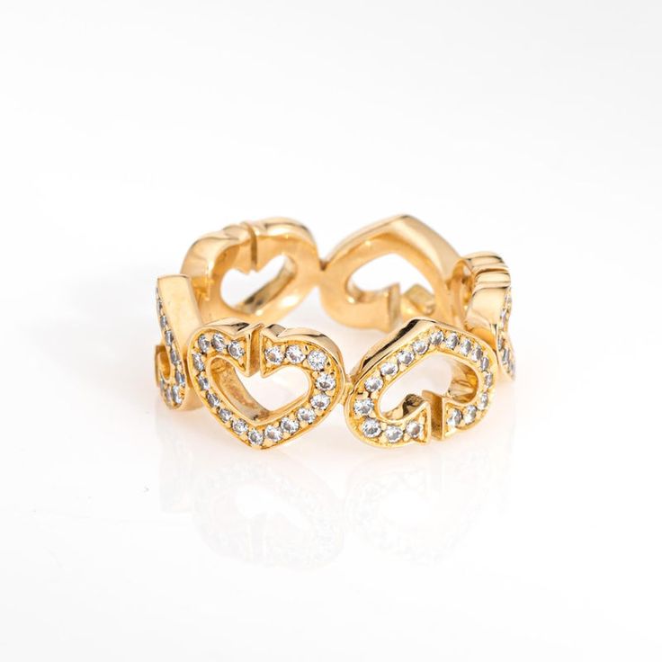 a gold ring with two hearts and diamonds in the middle, on a white background