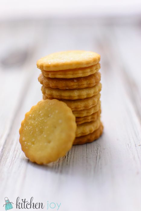 a stack of crackers sitting on top of a wooden table next to a plate of cookies