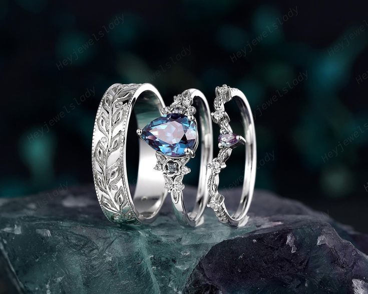 two wedding rings with blue topazte and white diamonds on the side, sitting next to each other