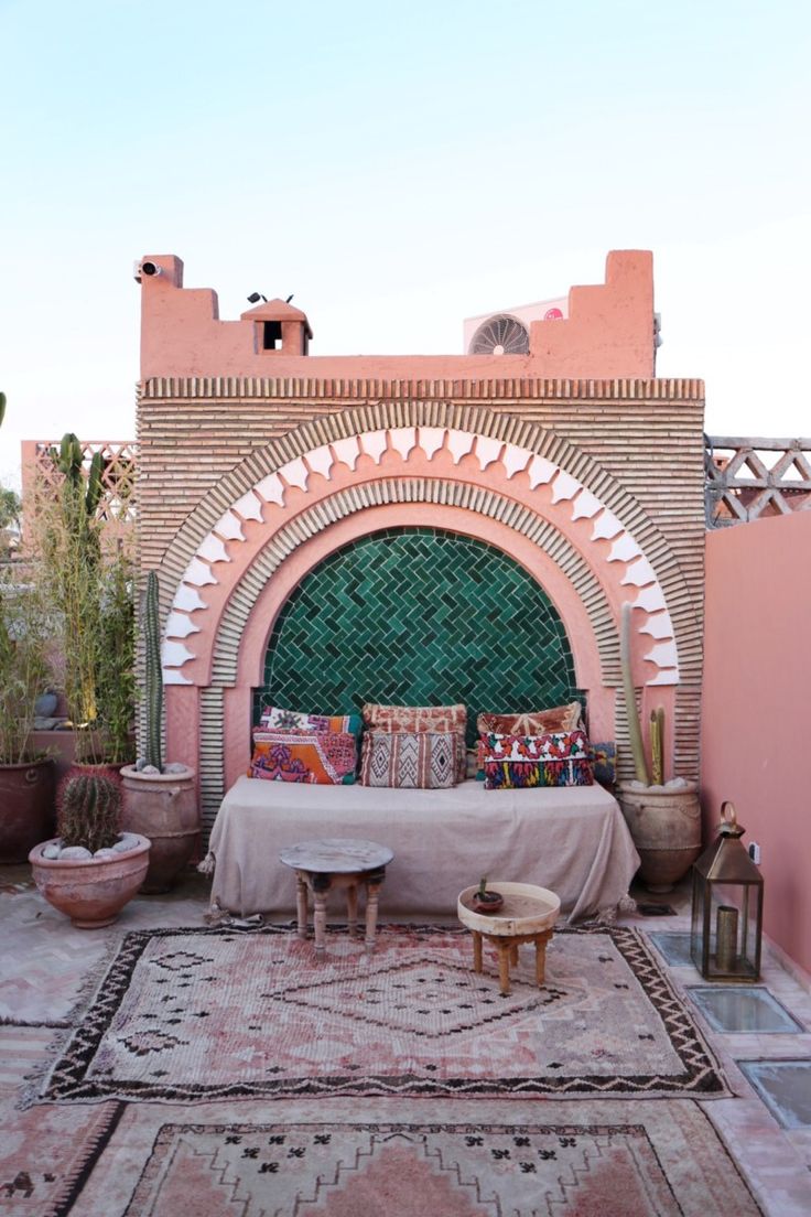 an outdoor area with a bed, table and potted plants on the side wall