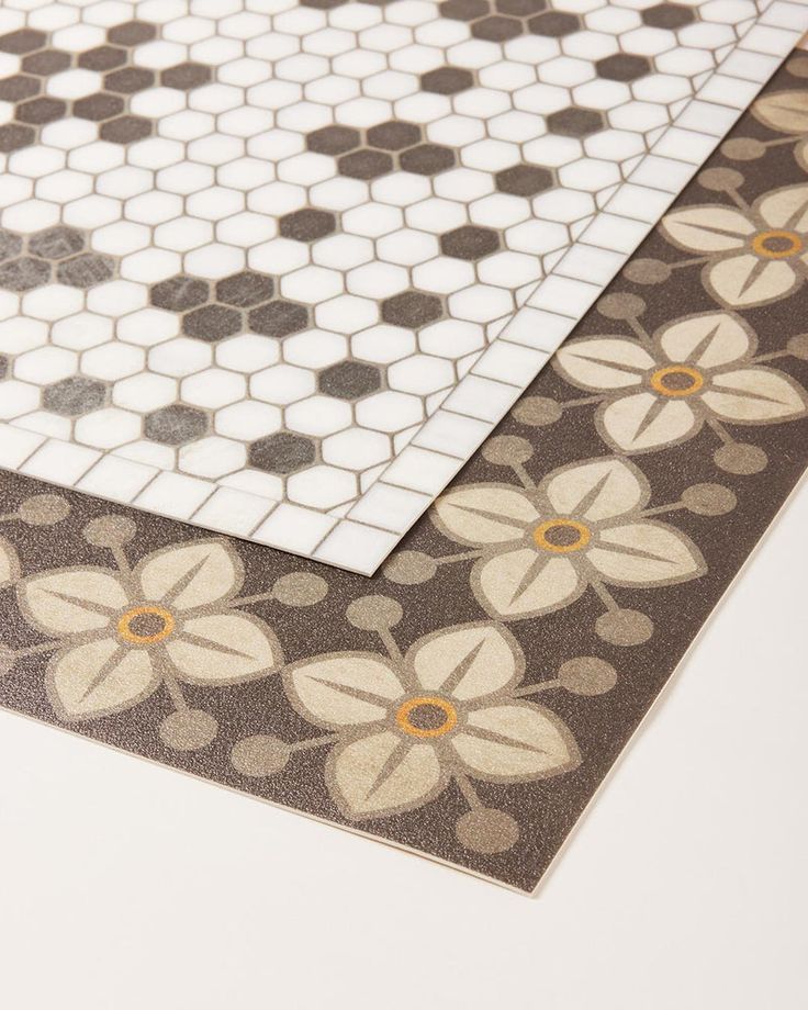 two tiles with flowers on them are laying next to each other, one is white and the other is brown