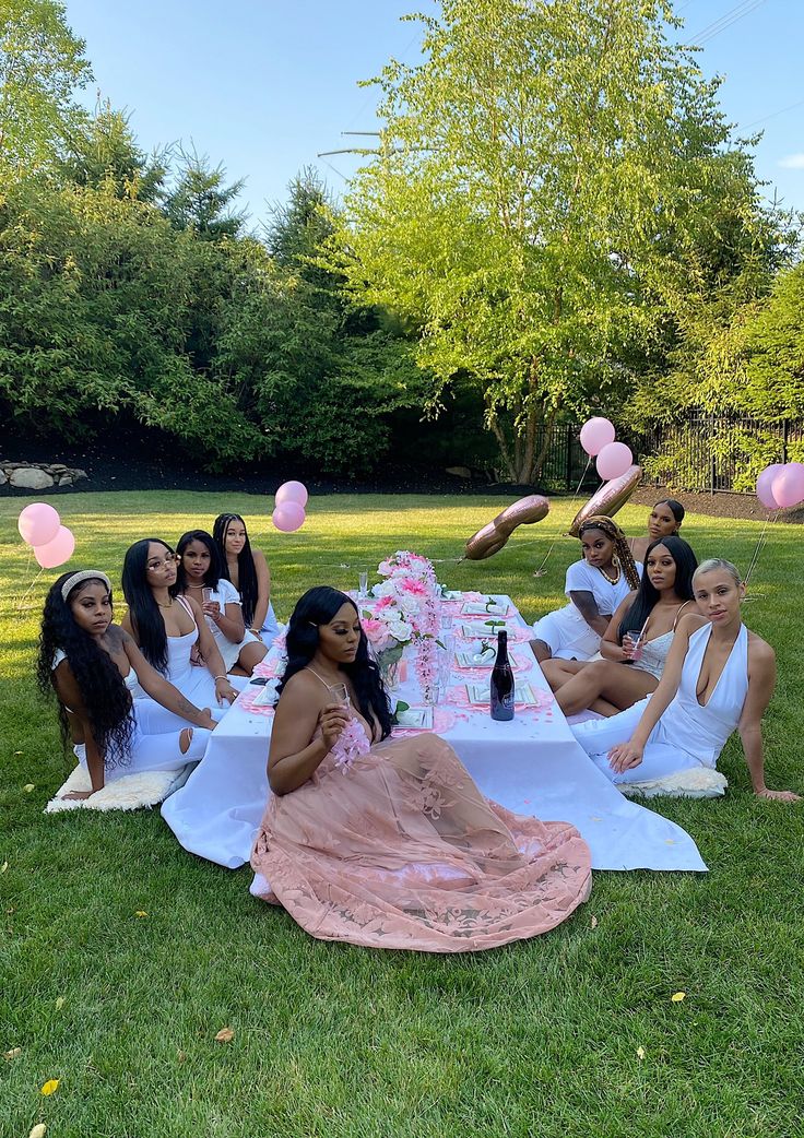 a group of women sitting on top of a lush green field next to each other