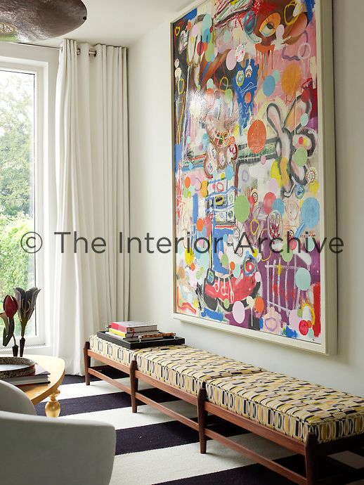 a living room filled with furniture and a large painting hanging on the wall above it