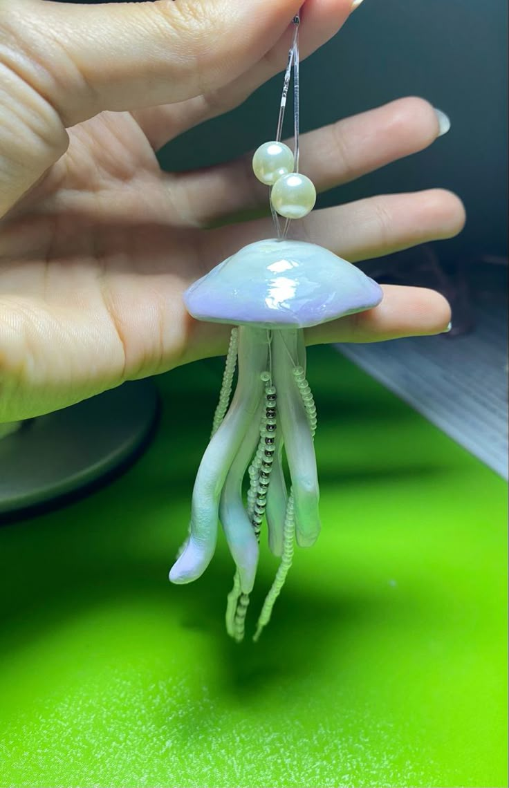 a hand holding an octopus keychain with pearls hanging from it