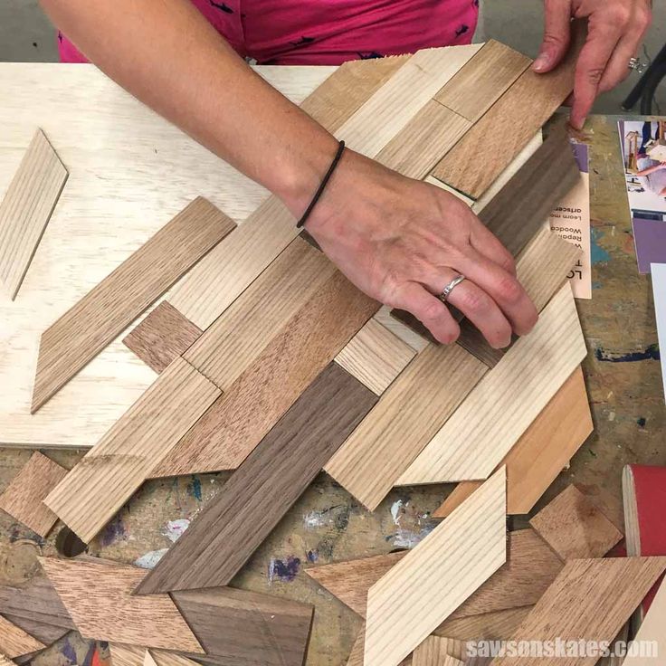 a woman is working on some wood pieces with her hands and the other hand touching them