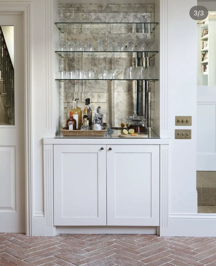 a kitchen with white cabinets and glass shelves