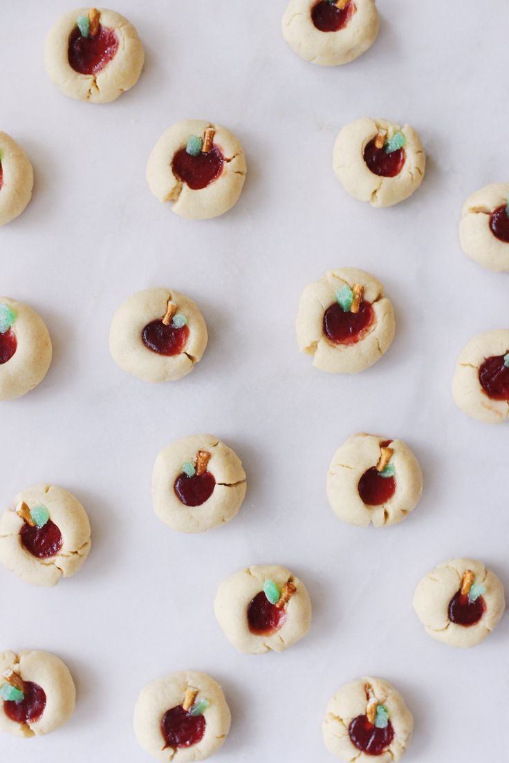 small cookies with jam on them are lined up in rows and ready to be baked