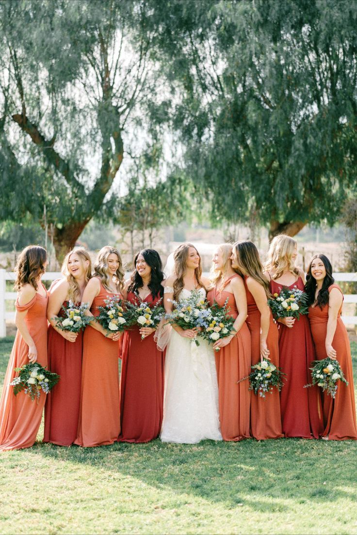 a group of women standing next to each other in front of a white picket fence