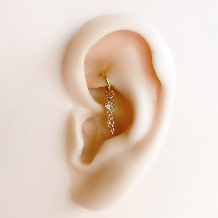 a pair of ear piercings on top of a white surface with one dangling from the end