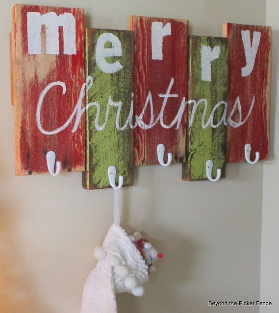 three wooden christmas signs hanging on a wall next to a white stuffed animal and a red santa clause ornament