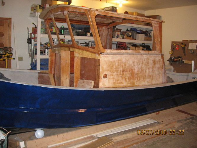 a boat being built in a garage with tools on the floor and shelves above it