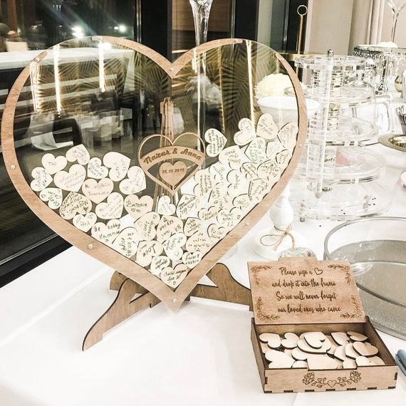 a heart shaped mirror sitting on top of a table next to wine glasses and other items