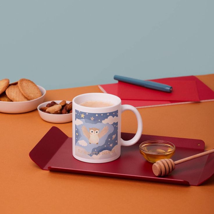 there is a cup and bowl with cookies on the table next to it, along with two spoons