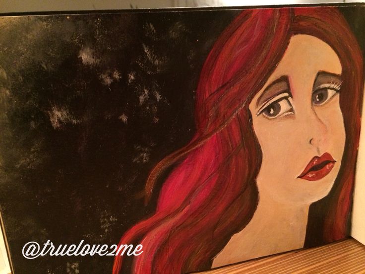 a painting of a woman's face with red hair on a wooden shelf in front of a black background