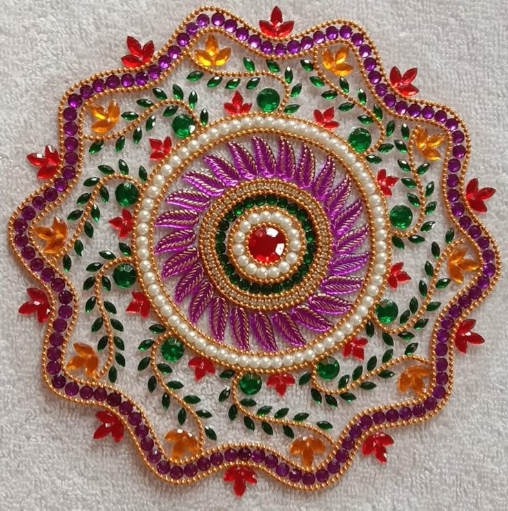 an embroidered piece with beads and flowers on white fabric, in the shape of a flower