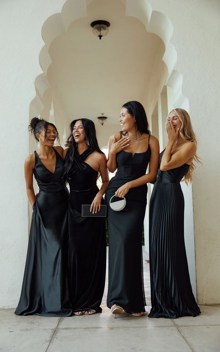 four women in black dresses standing next to each other