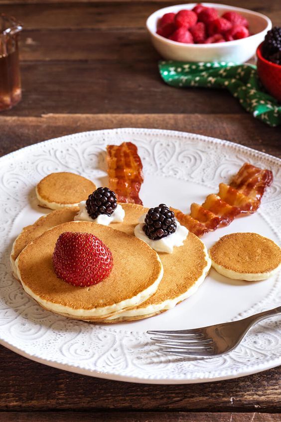 pancakes with fruit and bacon on them are ready to be eaten by someone at the table