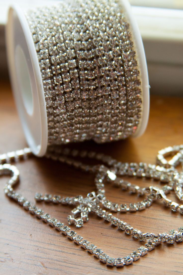 a spool of silver beaded ribbon sitting on top of a wooden table