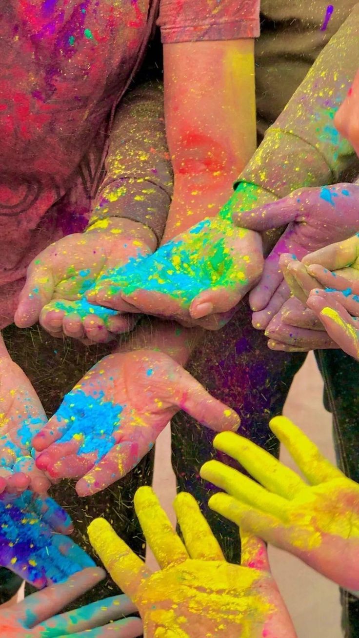 many people are covered in colorful powder and holding their hands together with the colors on them