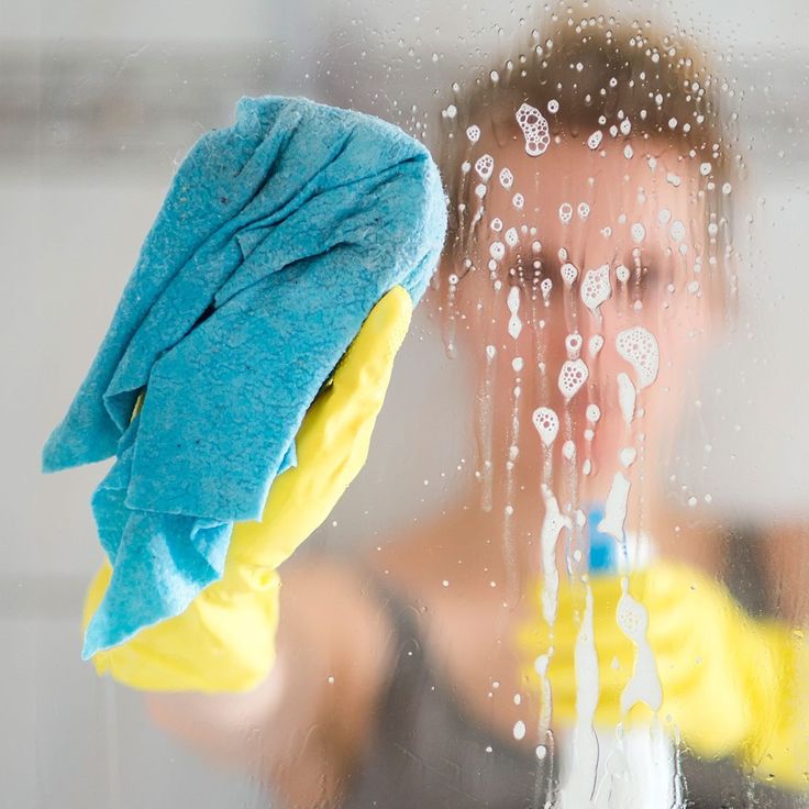 a woman is cleaning the window with a sponge and rag in front of her face