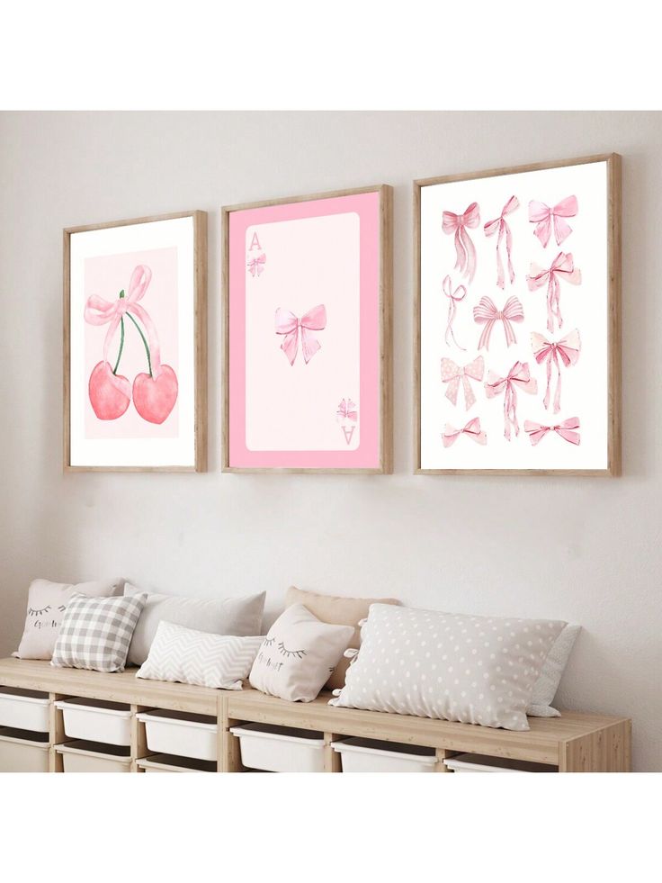 two pink paintings hanging on the wall above a bench with pillows and pillow cases in front of them