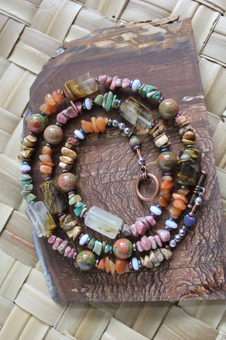 This stunner necklace measures 27.5 inches and is beaded with beautiful blue lace agate heishi beads, barrell style fire quartz beads, unakite round stone beads, and stone chip beads of:  Rhodonite, Turquoise, picture jasper, and aventurine.  Beads are separated with rainbow hematite disc beads and are mixed in between the different variety of stones.   A copper metal toggle clasp with two rainbow hematite hearts and 8 faceted rainbow hematite end beads finish off the design of this truly beautiful necklace. This necklace will make you happy wearing it as it has many different stones.   This is a healing stone necklace design.  It is truly a fun style of necklace to wear and looks great with many different colors.   Necklace is beautiful and was designed and beaded in our shop. Standard Fi Luxury Agate Faceted Beads Necklace, Luxury Traditional Agate Beaded Necklaces, Jade Long Necklace With Natural Stones, Long Jade Necklace With Natural Stones, Bohemian Jewelry With Ocean Jasper Gemstone Beads, Bohemian Ocean Jasper Gemstone Beads Jewelry, Colorful Round Agate Bead Jewelry, Colorful Round Agate Beads Jewelry, Bohemian Long Jade Necklace