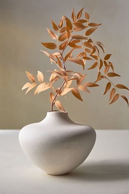 a white vase with a plant in it