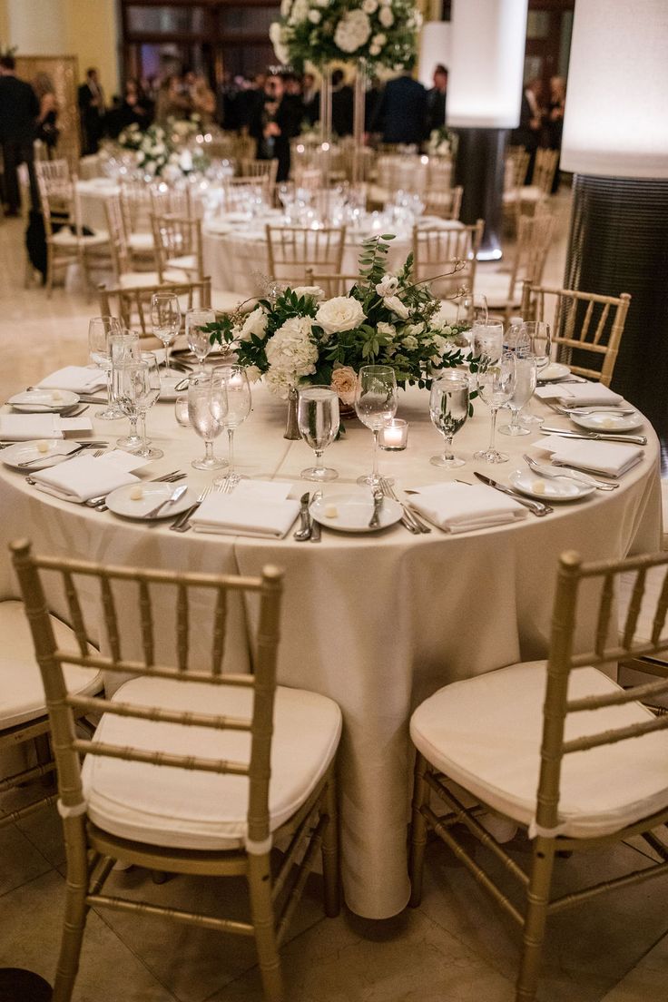 the tables are set with white linens and silverware for an elegant wedding reception