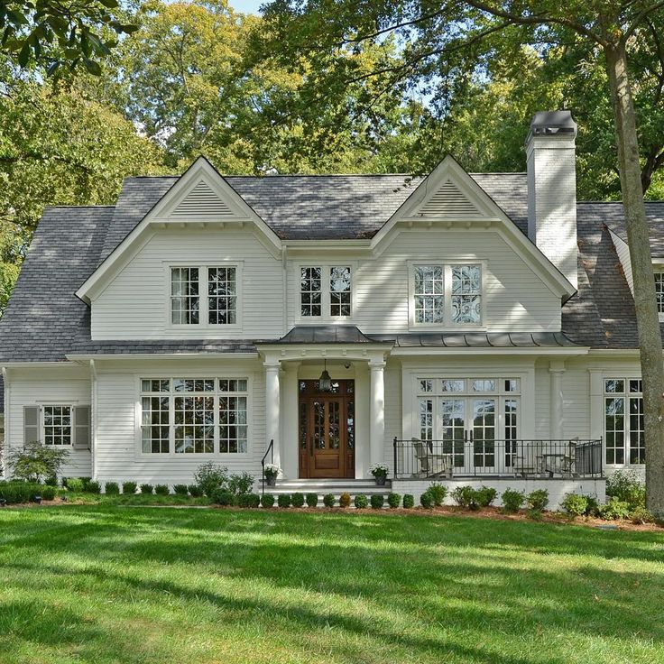 a large white house with lots of windows and grass in front of the door is surrounded by trees