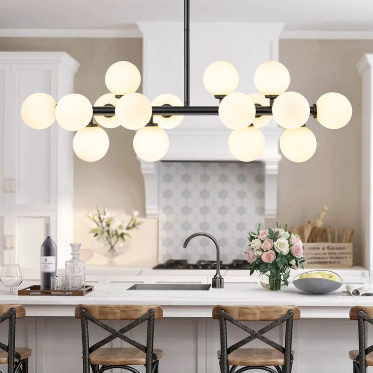 a kitchen island with chairs and lights hanging over it