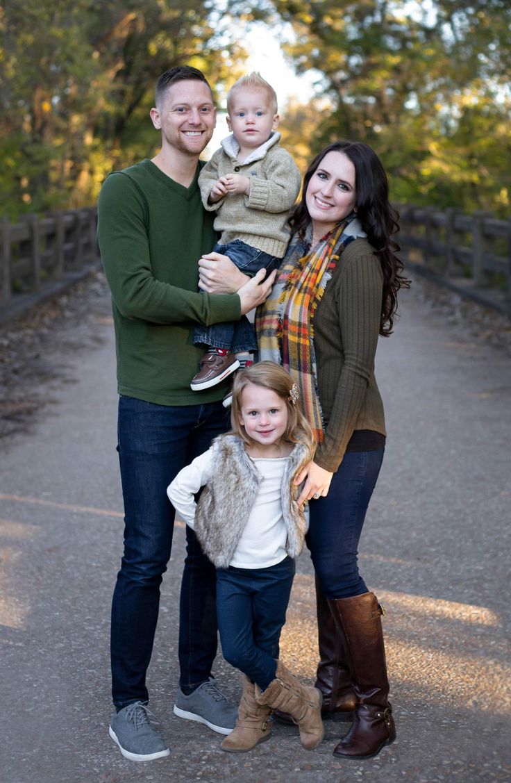 a family poses for a photo on a bridge in the fall with their toddler