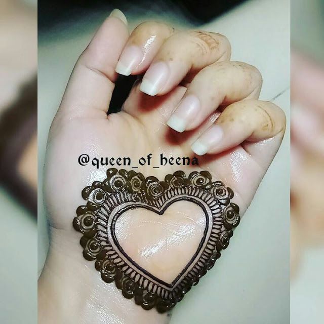 a woman's hand holding a hendi with a heart on it