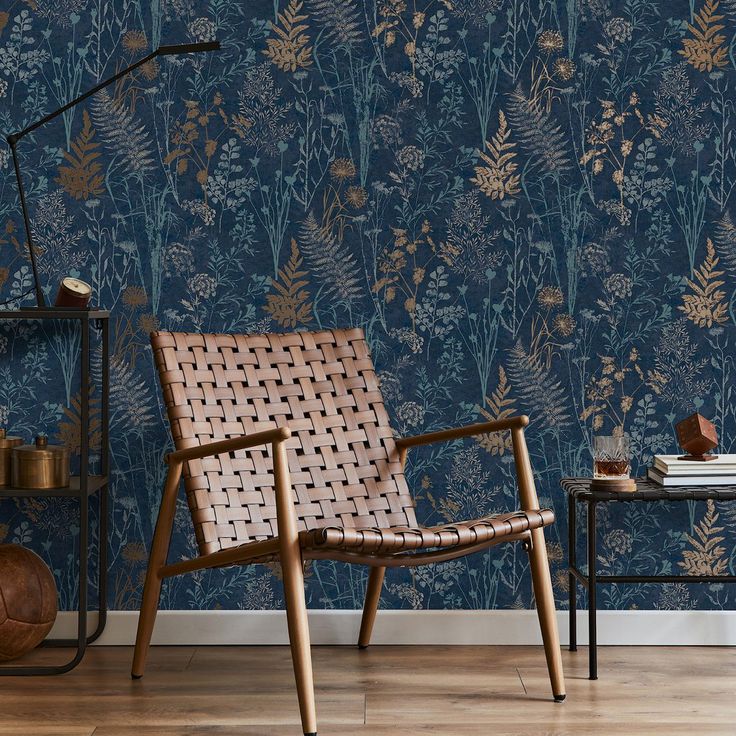 a chair sitting in front of a blue wallpaper with gold leaves and flowers on it