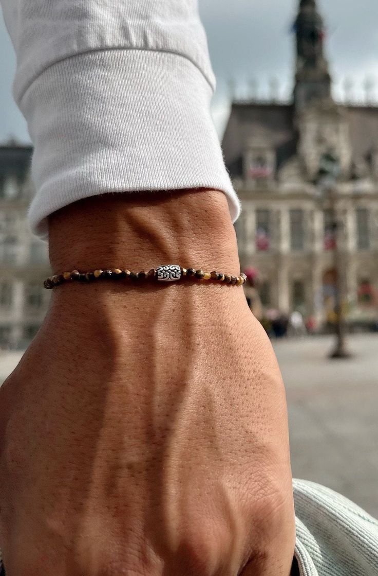 A Tiger Eye Beaded Bracelet for Men with a that is made with a silver metal part at the center in ethnic philosophy and minimal dimensions. All these materials are passed through an elastic cord. You can select between four available dimensions.  FInd them at Christina Christi Store. 👉 My Mens Bracelets Collection: https://etsy.me/2UunKla 👉 Express Shipping: https://etsy.me/3ikUnOM MATERIALS - Tiger Eye Beads 3mm. - Metal Parts. - Elastic cord. DIMENSIONS - You can choose four different dimens