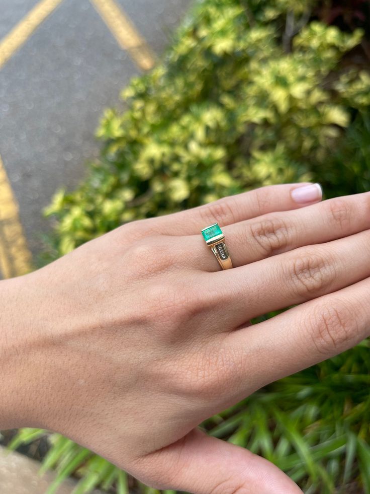 A unique Colombian emerald and diamond ladies' ring. A beautiful, medium-light green Colombian emerald weighing approximately 0.86-carats, with diamond accents on each side. The Colombian emerald is tension-set in a 14K yellow and white gold setting. Perfect for everyday use. Setting Style: Tension Setting Material: 14K Yellow & White Gold Gold Weight: 4.3 Grams Main Stone: Emerald Shape: Emerald Cut Weight: 0.86-Carats Clarity: Transparent Color: Medium Green Luster: Excellent - Very Good O 14k Gold Green Diamond Princess Cut Ring, Princess Cut Green Diamond Ring In 14k Gold, Green Princess Cut Diamond Ring In 14k Gold, Green Princess Cut Diamond Ring In Fine Jewelry Style, Fine Jewelry Green Princess Cut Diamond Ring, Green Princess Cut Diamond Ring Fine Jewelry, Green Princess Cut Diamond Ring, 14k Gold Emerald Ring For Proposal, 14k Gold Princess Cut Emerald Ring